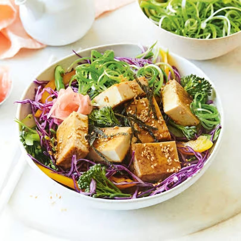 A vibrant tofu poke bowl with purple cabbage, green onions, and pickled ginger.